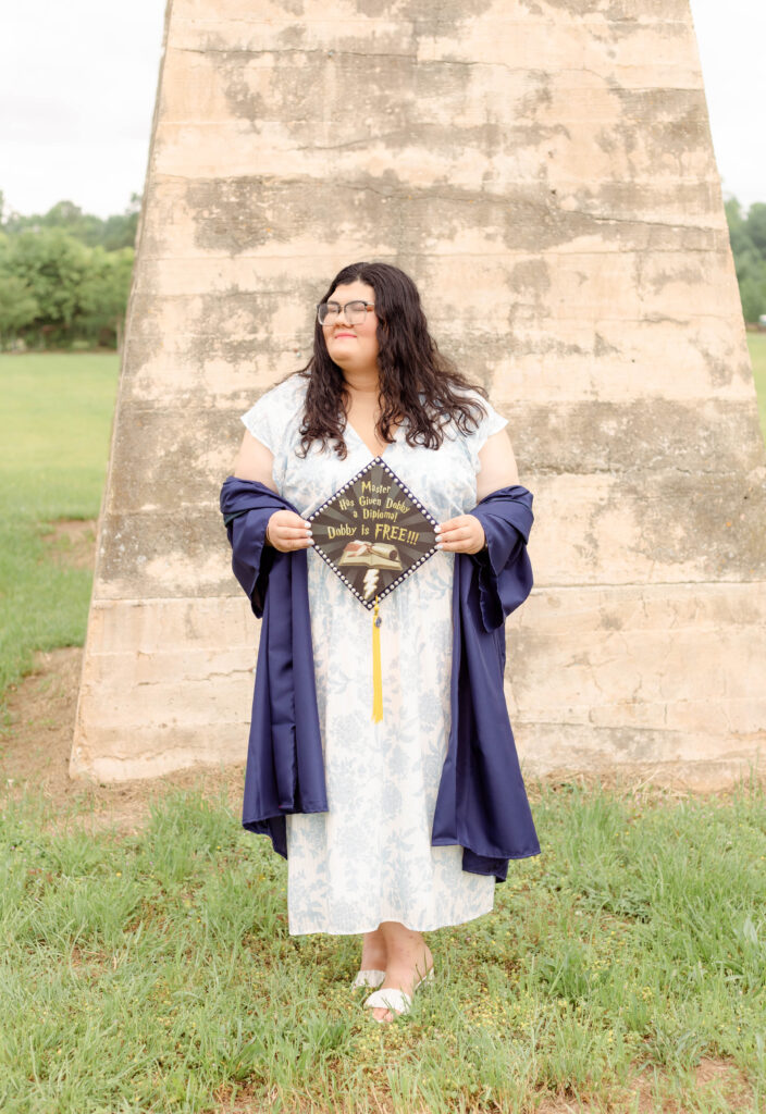College graduate holding up a decorated cap during a graduation photo session in North Augusta, South Carolina