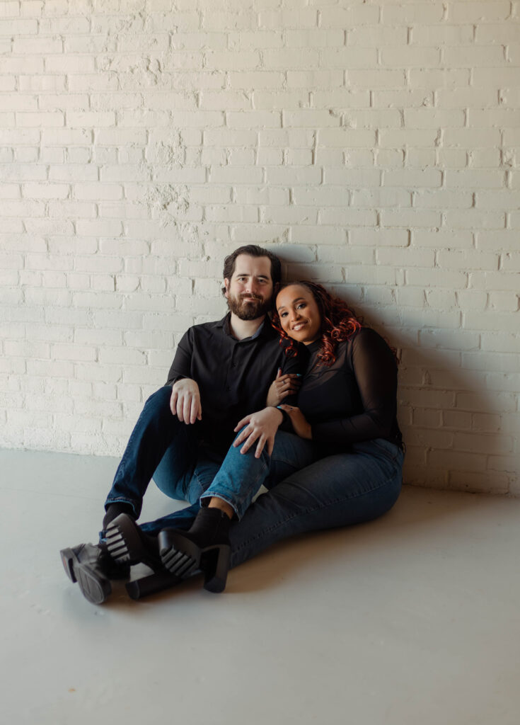 Engaged couple sitting close and smiling during their studio engagement session in Augusta, Georgia