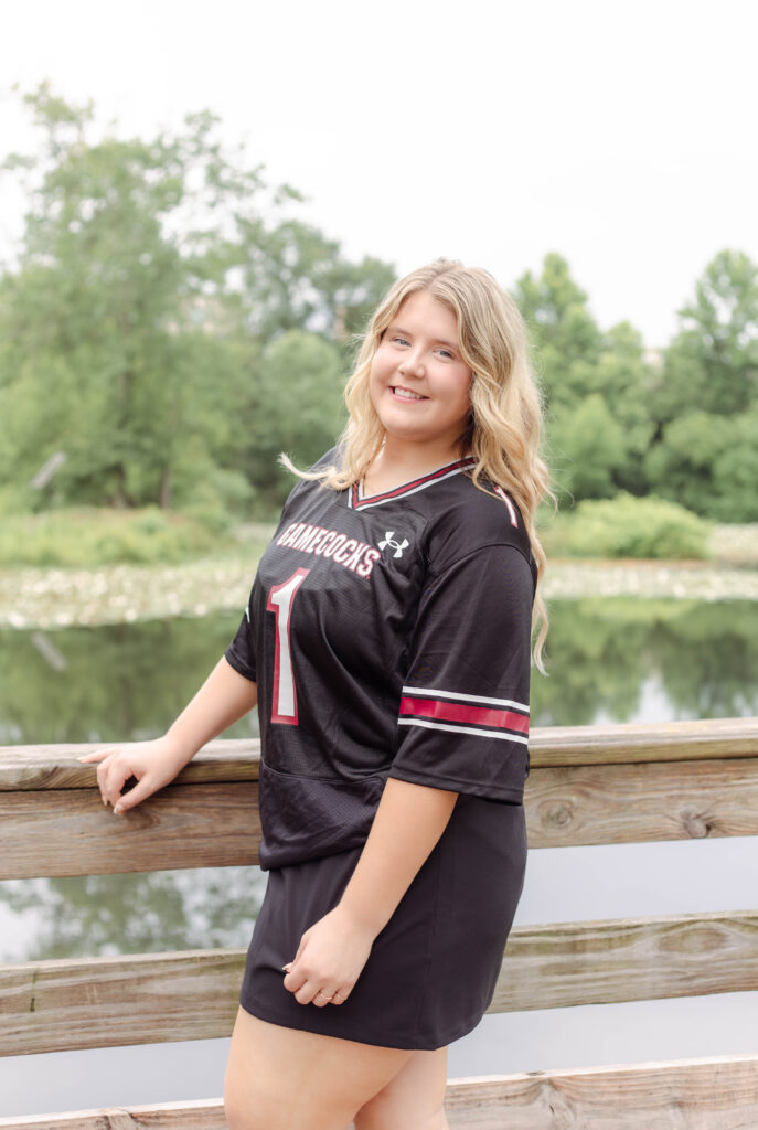 North Augusta High School senior posing for graduation photo session with University of South Carolina jersey at Brick Pond Park in North Augusta, South Carolina