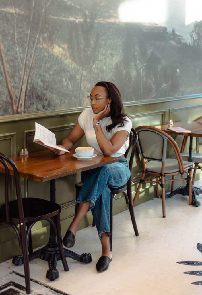 Author sitting at cafe table for branding session with her book and a coffee