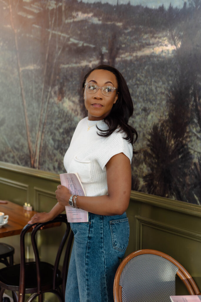 Author looking away while holding her book inside a cozy café setting