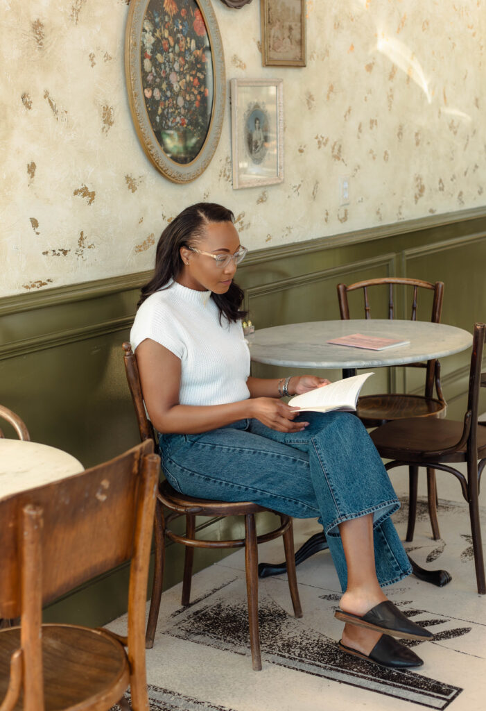 Author flipping through her book at a café table during a branding shoot at Rooted Coffeehouse in Martinez, Georgia