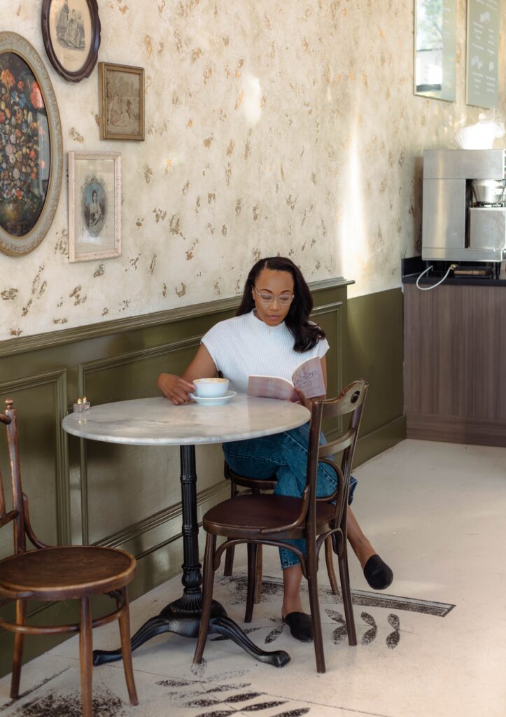 Author reading her book in a softly lit coffeehouse setting at Rooted Coffeehouse in Martinez, Georgia