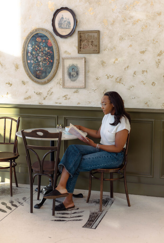 Author looking through her book while sitting at a café table during a branding shoot at Rooted Coffeehouse in Martinez, Georgia