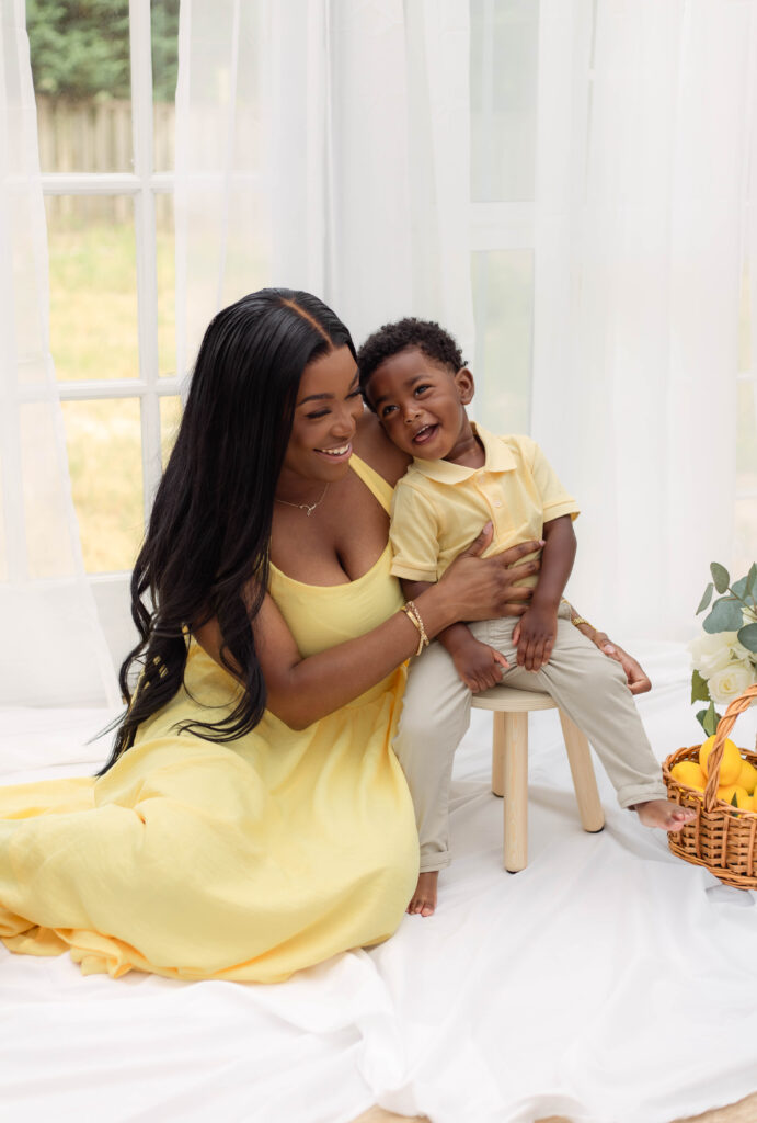 Son sits on a little stool with his mom next to him smiling