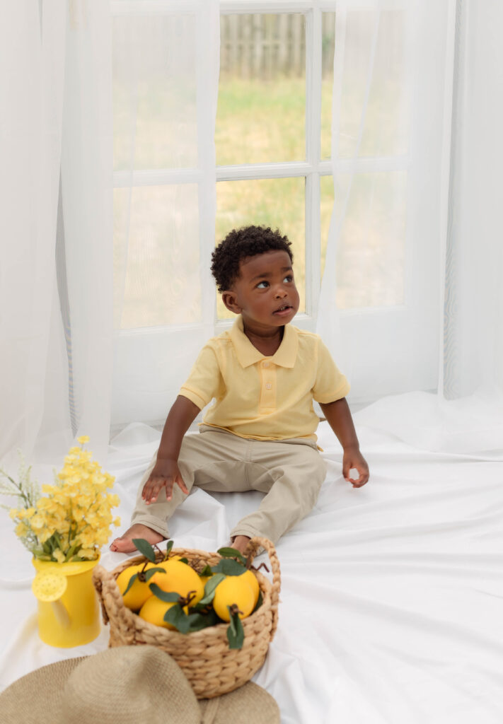 Little boy sitting on a white sheet with lemons nearby