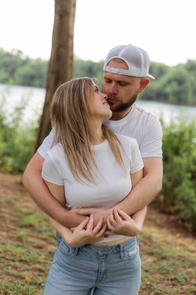 Man holds his fiancée from behind for engagement photo session