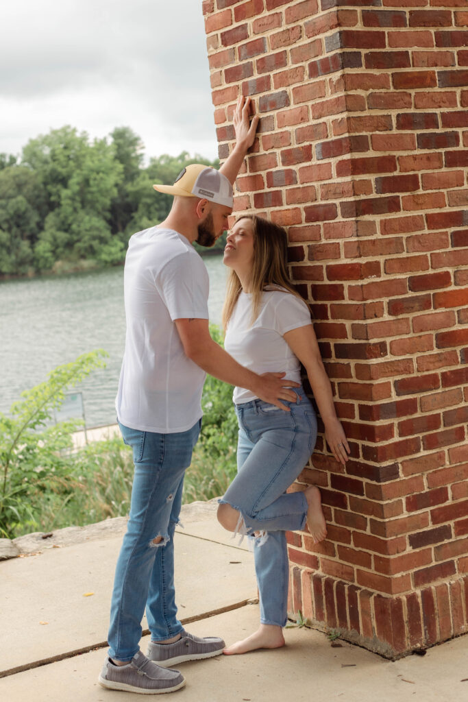 Man leans on brick wall towards his fiancée