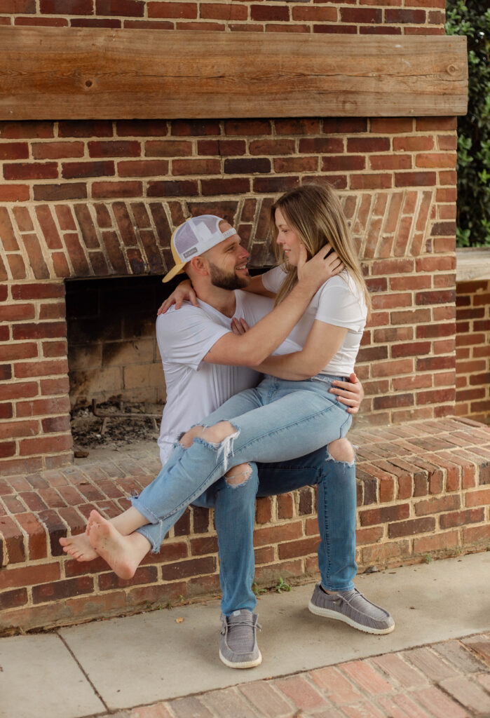 Woman sitting on her fiancé's lap for engagement session in North Augusta