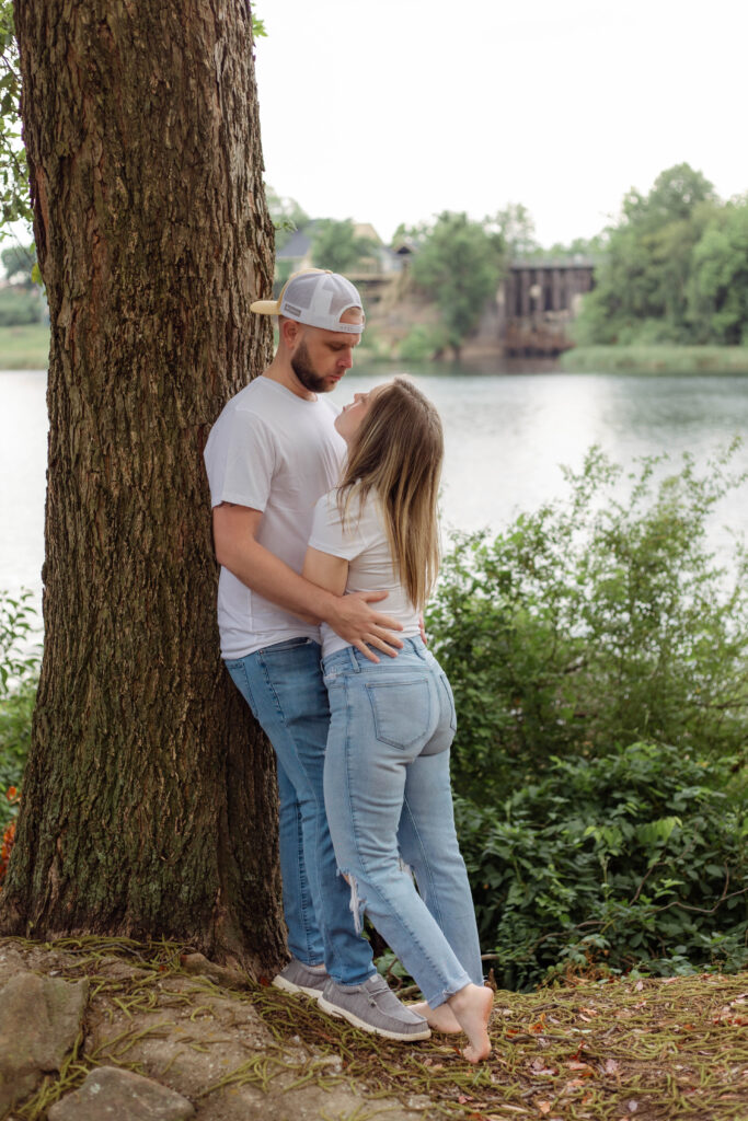 Leaning against a tree a man holds his fiancée