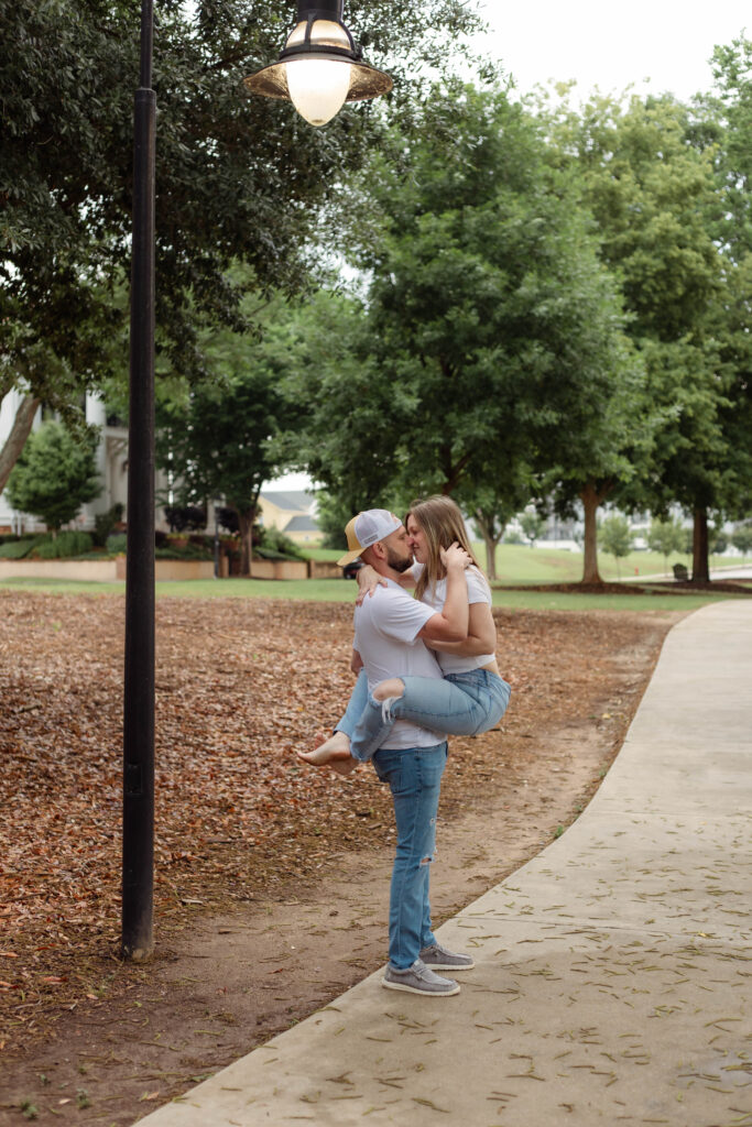 Man holding his fiancée while kissing her near lamppost