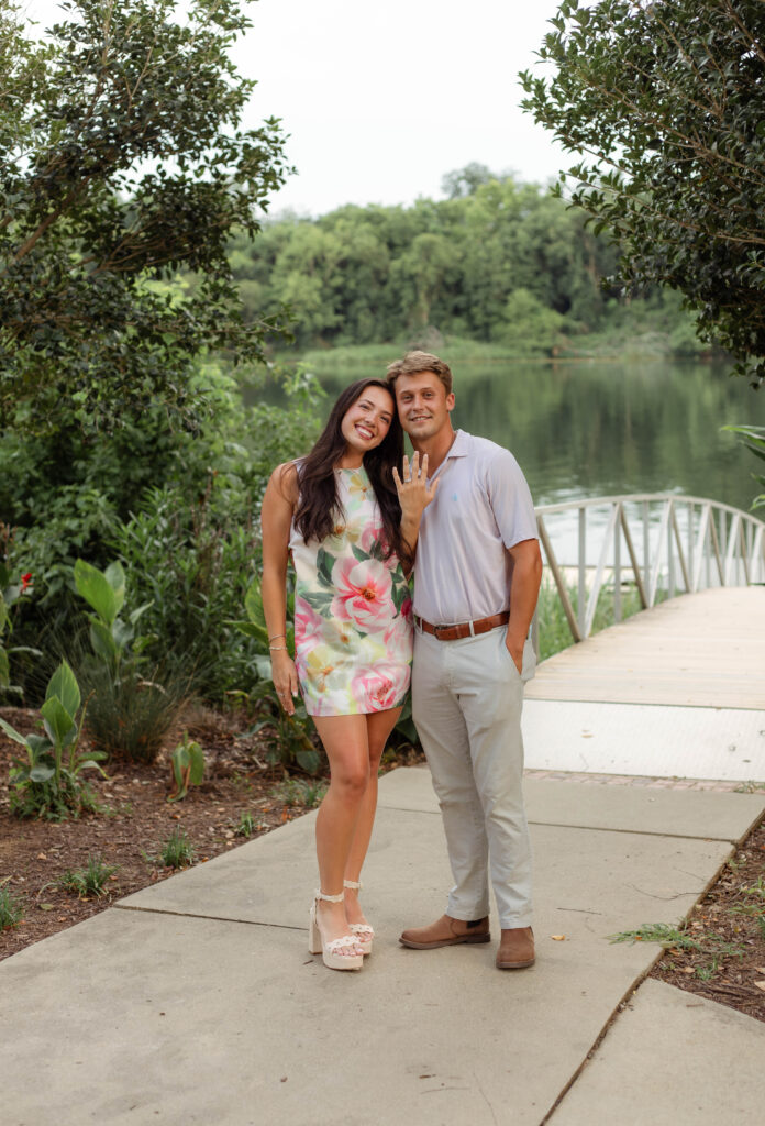 Couple smiling and showing off the engagement ring