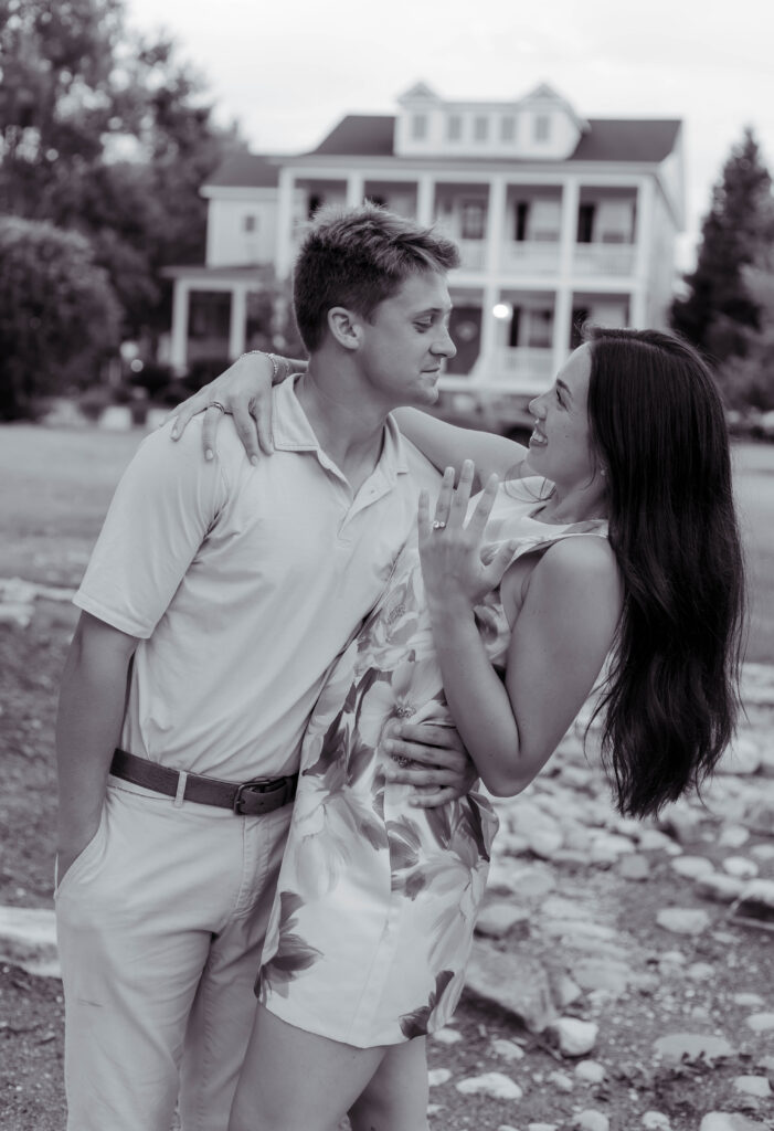 Black and white photo of a couple posing in front of house