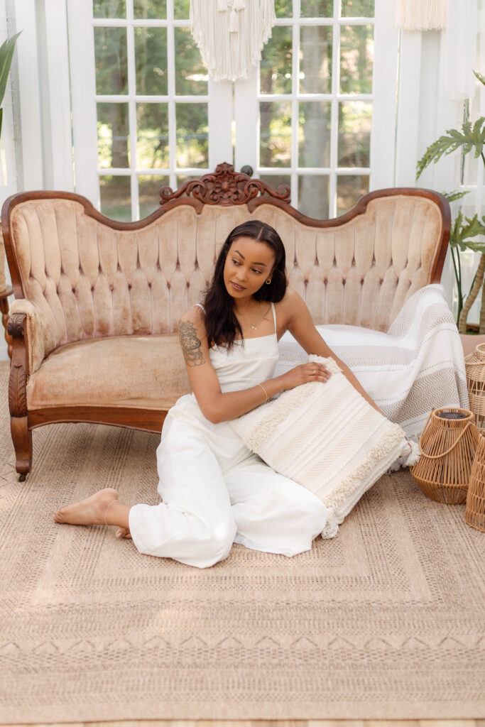 Woman in a white jumpsuit posing in a boho-inspired studio at The Glass Studio in North Augusta, South Carolina