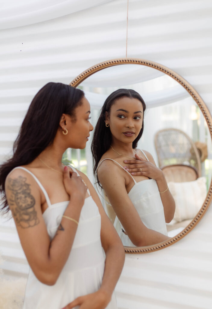 Model posing in front of mirror in a white jumpsuit
