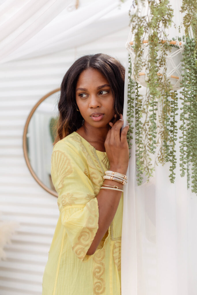 Up close portrait of a model wearing a yellow dress in a boho-themed photography studio