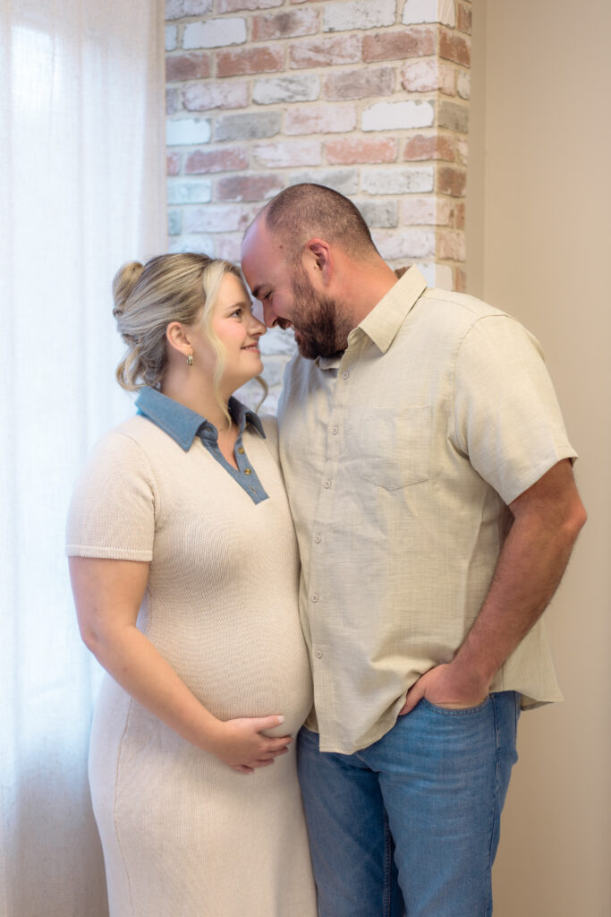 Expecting couple touching foreheads for photo session