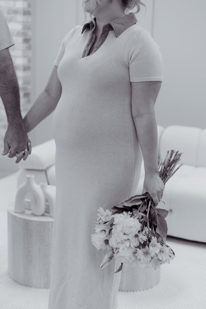 Black and white photo of an expecting mother holding flowers