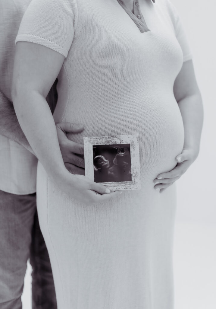 Close up of a couple holding a framed photo of an ultrasound