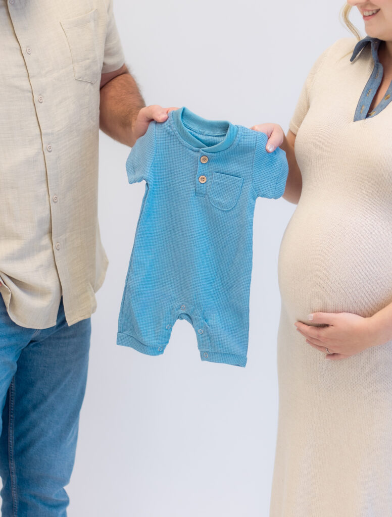 Close up of a blue onesie as each parent holds either side