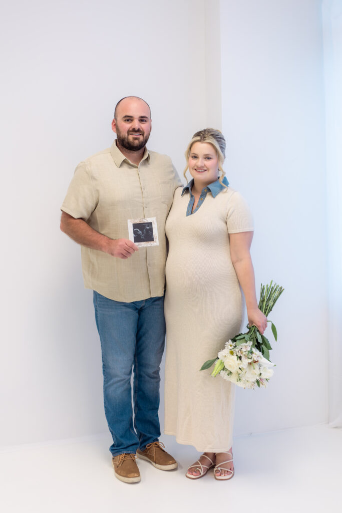 Couple holds framed ultrasound photo and flowers to announce pregnancy