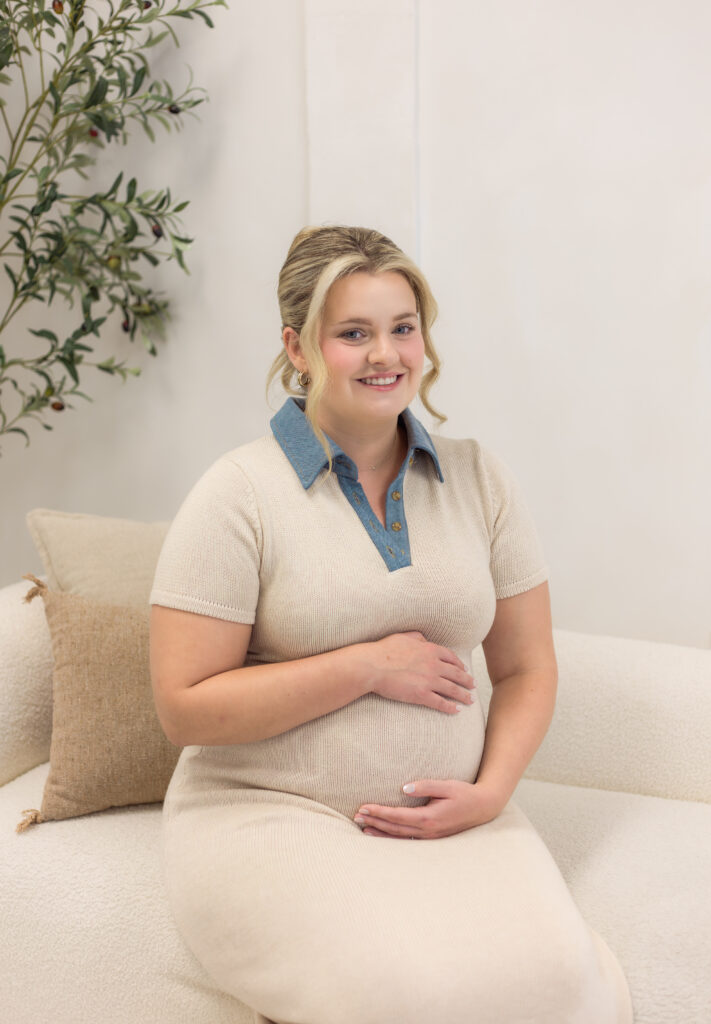 Expecting mother holds her stomach with a smile