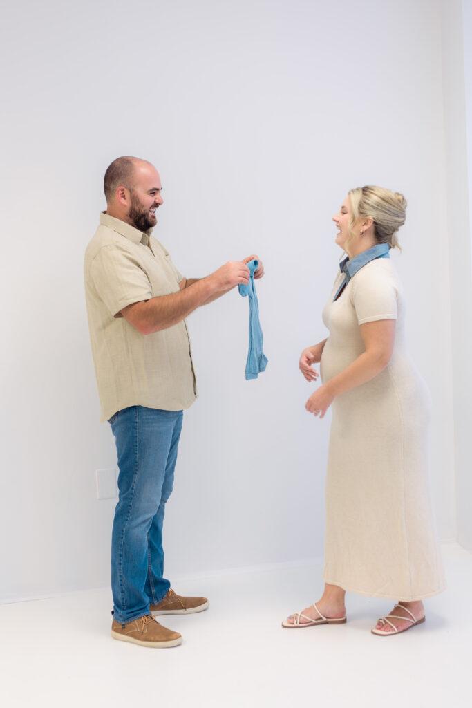 Man holds blue onesie to his wife