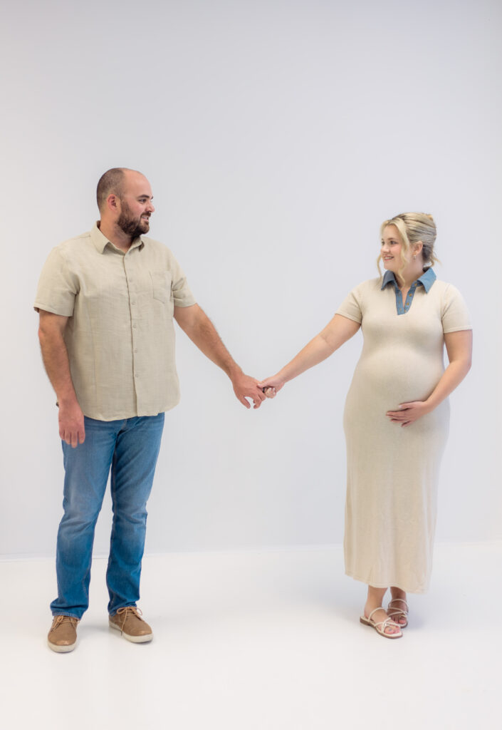 Couple holds hands while showing off pregnant belly