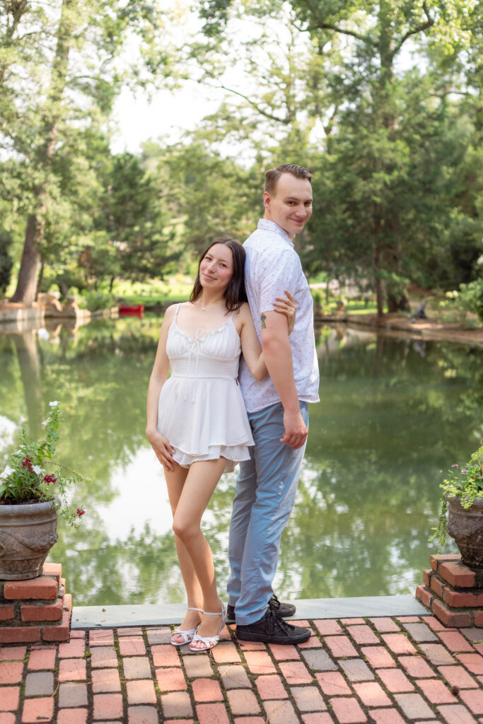 Couple standing together in front of European inspired pond