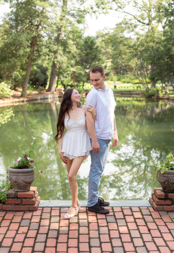 Woman holds her husband's arm in front of body of water