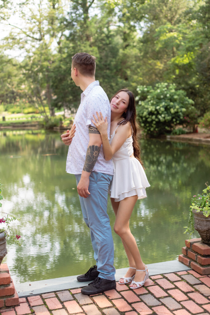 Woman holds onto her partner as he looks out over the water