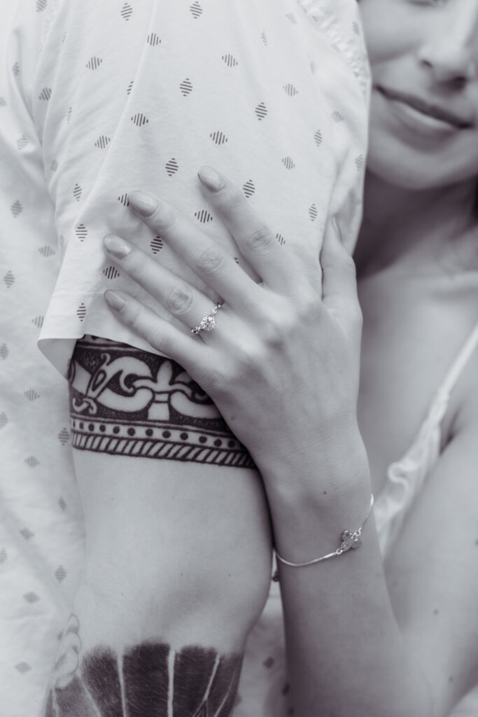Black and white up close photo of a woman's ring while hugging her partner