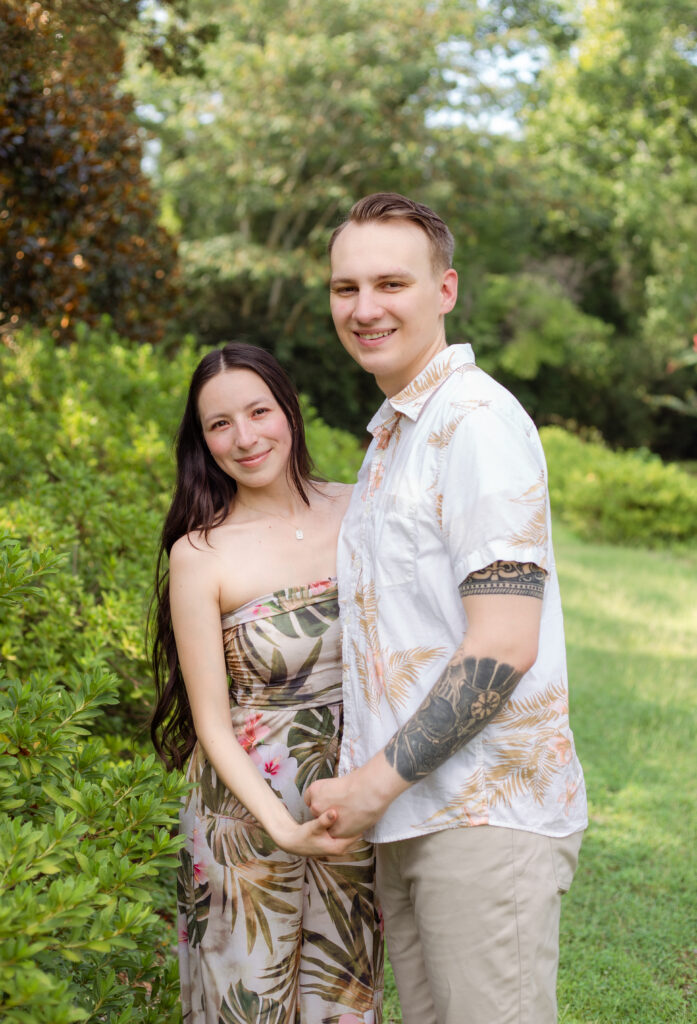Couple posing together in front of lush greenery