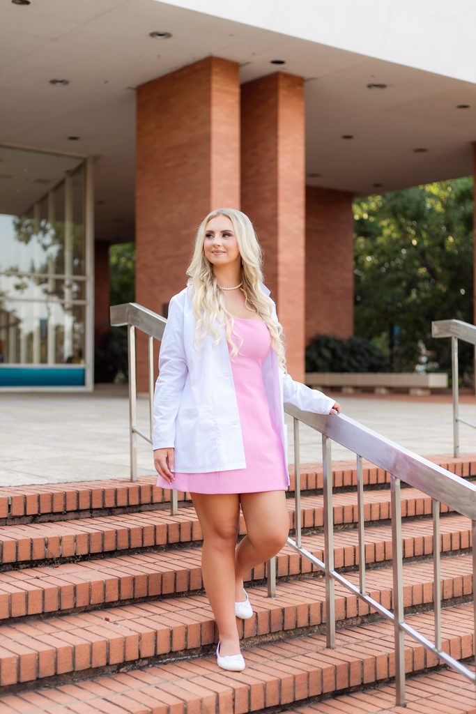 Augusta University grad walks down stairs with white coat on