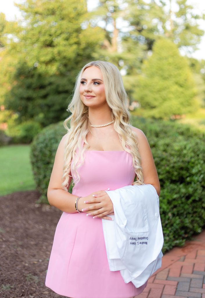College grad posing with white coat and pink dress