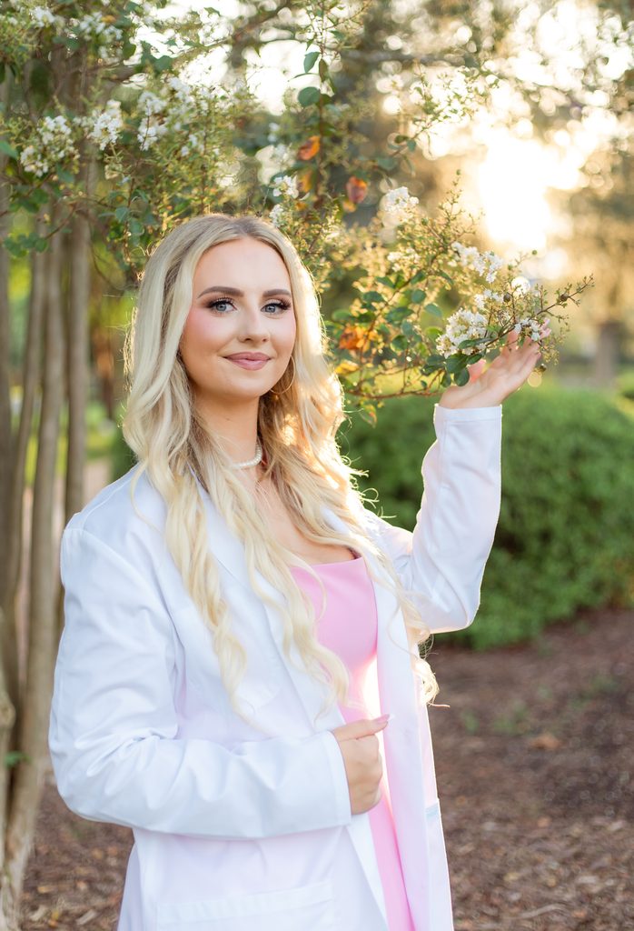 College grad holds white flowers for golden hour photo session