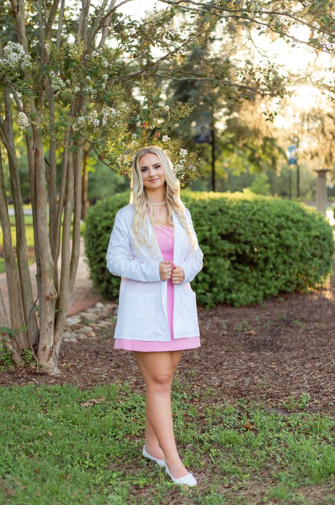 College graduate stands with white coat on for photo session