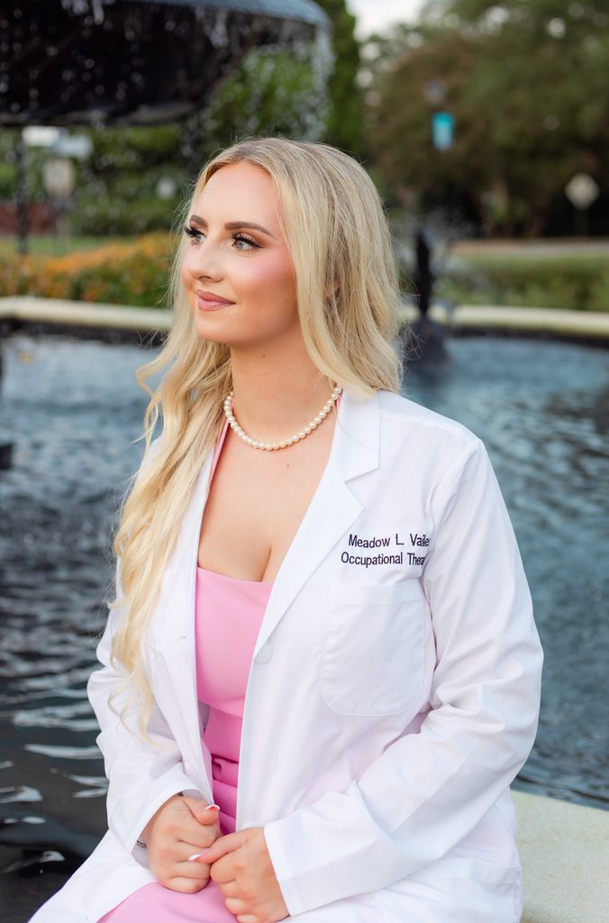 College graduate posing in front of fountain at Augusta University campus