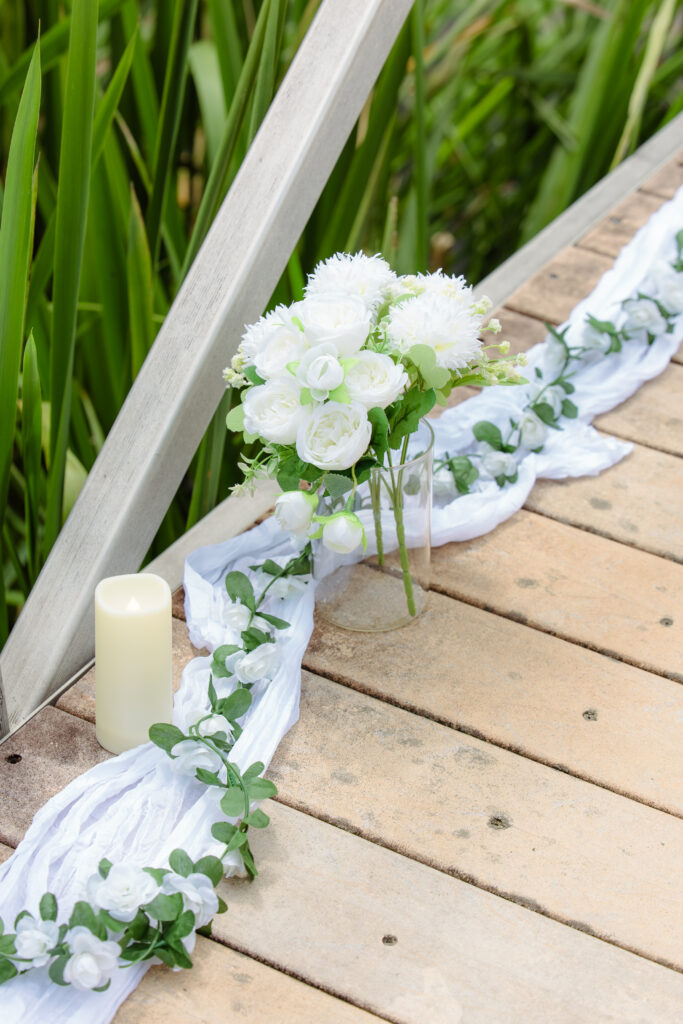 Close up of flowers, candles, and fabric decorations on a dock for proposal