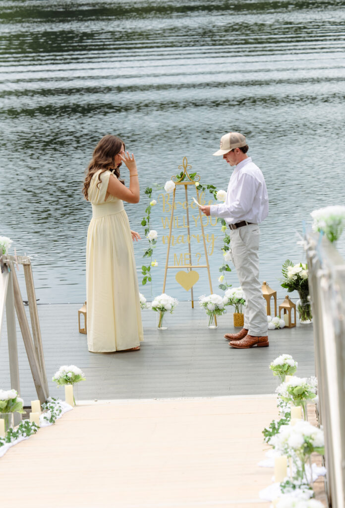 Woman wipes some tears as her boyfriend is reading a note before proposal at Hammond's Ferry